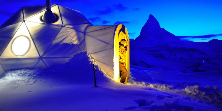 Snow domes on high open ground in the Alps, mountains behind them